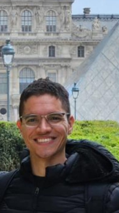 Lucas Marcelino Campos Ferreira sorrindo em frente a um prédio histórico.